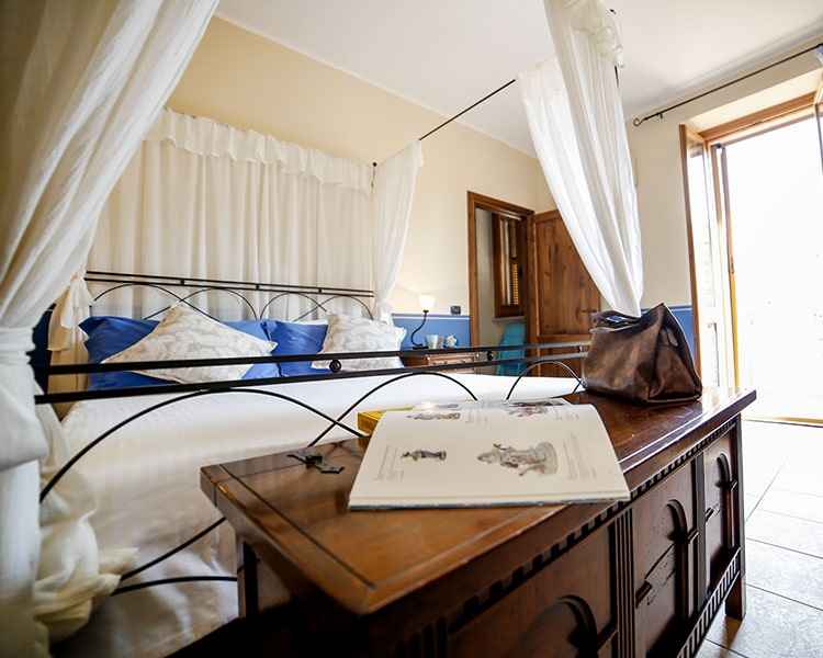A four-poster double bed dominates the room - Le Muse holiday apartment Bevagna, Umbria, Italy
